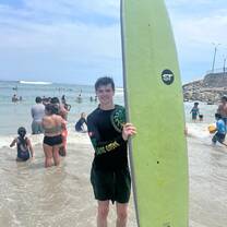 a boy standing with a surf board