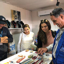 Students and a humanitarian worker looking at decorative objects on a table.