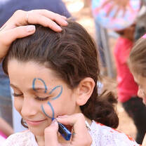 A child having a flower face-painted over one eye
