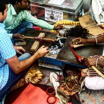 Three people making tools over coals