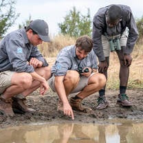 3 students tracking a wild animal using footprints 