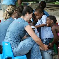 Volunteers doing childcare services by teaching importances of washing hands.