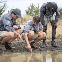 3 students tracking a wild animal using footprints 