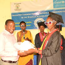 single mother dressed in graduation gown receiving her diploma