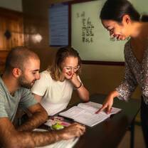 Teacher helps two students looking at a textbook