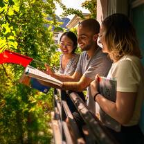 Two students and a teacher study on a balcony