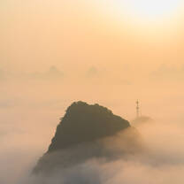 A cloud inversion and orange cloud below a rising sun