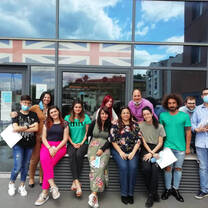 teachers in front of a building holding certificates 
