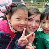 Teacher in China giving peace sign with two young children