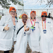 four people in orange caps and lab coats