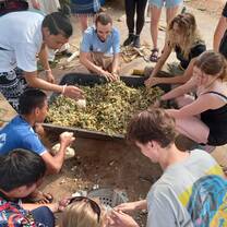 a group sit around a giant bowl of food