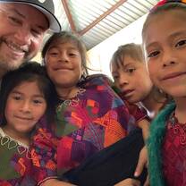 Man surrounded by young children smiling