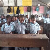 three children sitting at a desk in a classroom