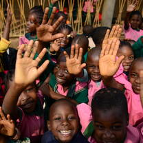young children raising their hands towards the camera