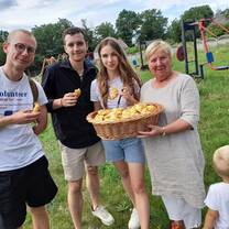 3 volunteers in Lipianka with an older woman holding a basket of bread 