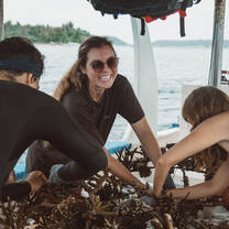 A shot of 3 interns all attaching coral to a coral structure on the boat.
