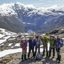 NOLS students stand for a photo in front of a snow capped peak