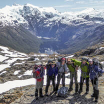 NOLS students stand for a photo in front of a snow capped peak