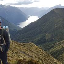 Student stands in front of a beautiful mountainscape 