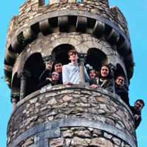 Students look down at the camera from a historical tower in Portugal