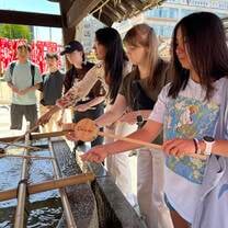 girls dipping wooden spoons into water