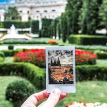 Student holds up a Polaroid picture amongst beautiful Prague garden
