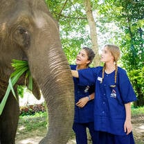 Two students in awe while touching an elephant