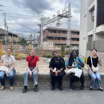 A group of CET Japan students sitting on an edge by a train station track