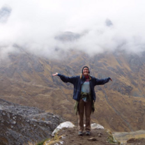 a girl stands with her arms outstretched in front of a mountain