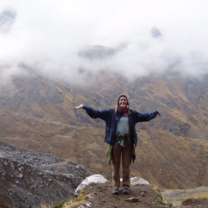 a girl stands with her arms outstretched in front of a mountain