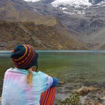 a hiker looks out at a lake 