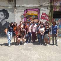 CET Brazil students standing in front of wall art with professor and a movement leader 