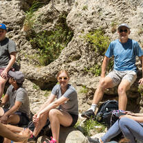 LITA students smiling at the camera while sitting on rocks at a resting point during a hike through the mountains