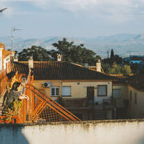 Two women and a small child looking out from their terrace over the town, with the mountains in the background