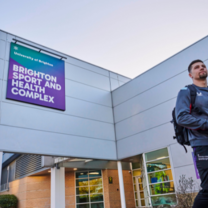 Student outside the Sports Centre at Falmer Campus 