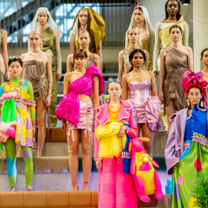 Fashion models lined up showcasing the bright colours of student work 