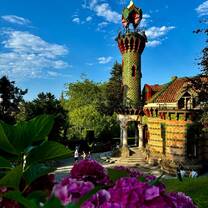 A stunning photo of El Capricho de Gaudí, a vibrant and ornate building in Spain surrounded by lush greenery and blooming purple flowers, showcasing the architectural beauty and cultural exploration possible with RVF International's Teach English in Spain program.