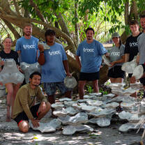 a group of volunteers presents 3D build artificial reef modules surrounded by lush greenery