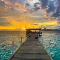 the sun sets behind a Jetty and illuminates the sky
