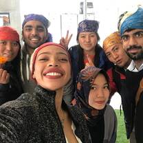 Volunteers from around the world clicking a picture together during a trip to a Gurudwara in New Delhi while participating in our Volunteer & Travel Program where they cover 10+ cities across India while participating in action-orientated impactful volunteering activities along with cultural immersion through travel to historic monuments, participating in art & food related workshops and much more
