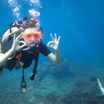A person underwater making the 'OK' sign with their hand