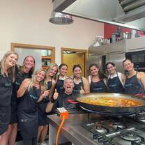 Volunteers stand by a pan of paella