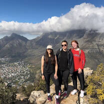 Three volunteers stand atop a mountain in South Africa