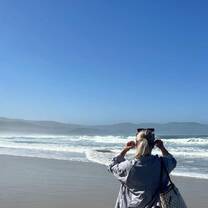 A volunteer adjusts her sunglasses while  looking out over the waves and bright blue sky of South Africa's beaches