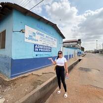 Volunteer posing outside Grand Mustard Seed Montessori School