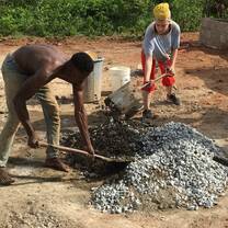 Construction volunteers mixing concrete on site