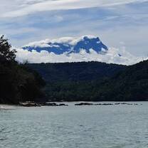 Mount Kinabalu’s snowcapped peaks rising above the forested hills of Pandan-Pandan Island
