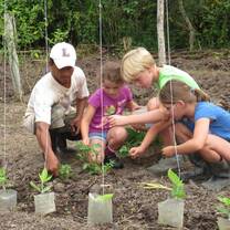 woman taking care of a vegetable garden with 3 children