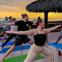 group of people doing yoga at sunset on the beach