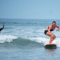 woman surfing with instructor celebrating